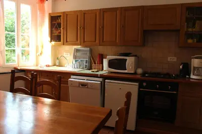 a kitchen with wooden cabinets and a table and a microwave at Au Coeur de Rennes Gîte in Rennes-les-Bains