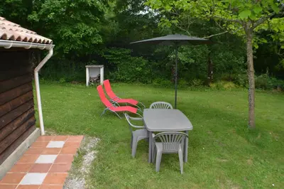 a table and chairs with an umbrella in a yard at Les Divines Cascades in Roquefort-les-Cascades