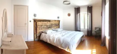 a bedroom with a large bed with a wooden headboard at LA BOURDETTE in Saverdun