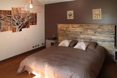 a bedroom with a large bed with a wooden headboard at LA BOURDETTE in Saverdun