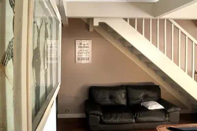 a black leather couch sitting under a staircase at LA BOURDETTE in Saverdun