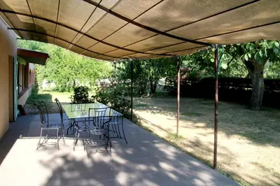 a patio with a table and chairs under a roof at LA BOURDETTE in Saverdun