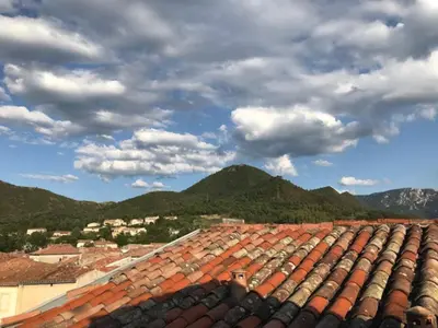 a group of roofs with mountains in the background at Modern Boulangerie, large 6 bedroom village house in Quillan