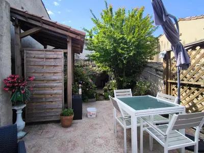 a patio with a table and chairs and an umbrella at Maison des Remparts nichée sous la Cité in Carcassonne