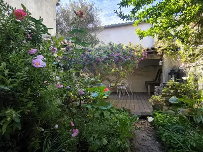 a garden with flowers and a table and chairs at Maison des Remparts nichée sous la Cité in Carcassonne