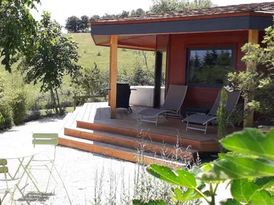 a cabin with a deck with chairs and a table at Cabanes Trésors de Campagne,spas privatifs in Villarzel-du-Razès