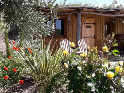 a small wooden house with two chairs in a garden at Cabanes Trésors de Campagne,spas privatifs in Villarzel-du-Razès