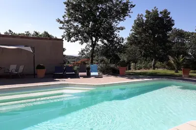 a large swimming pool with blue chairs and trees at Cabanes Trésors de Campagne,spas privatifs in Villarzel-du-Razès