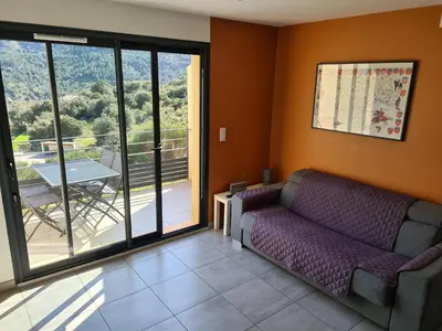 a living room with a couch and a balcony at LE COSY GITE in Duilhac