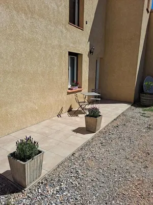 a patio with two potted plants next to a building at Chambre d'hôte in Cucugnan