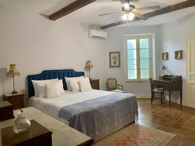 a bedroom with a bed with a ceiling fan and a desk at Sainte-Hélène Chambres d'Hôtes & Appartement in Olonzac