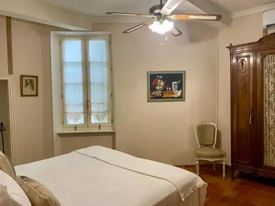 a bedroom with a bed and a ceiling fan and a chair at Sainte-Hélène Chambres d'Hôtes & Appartement in Olonzac
