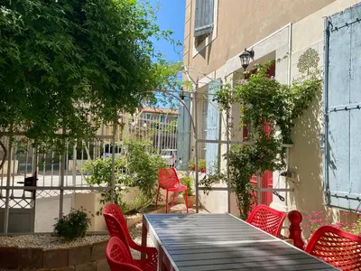 a patio with red chairs and a table and a building at Sainte-Hélène Chambres d'Hôtes & Appartement in Olonzac