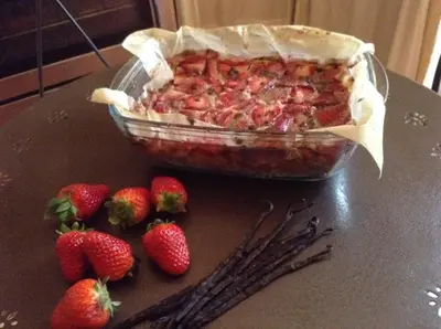 a pie in a dish on a table with strawberries at Aux Anges Gardiens in Carcassonne