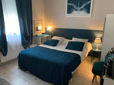 a bedroom with a large bed with a blue blanket at La Turenne in Narbonne