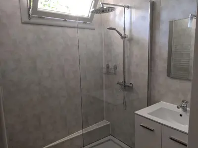 a shower with a glass door next to a sink at LA MAISON MIRAVA in La Caunette