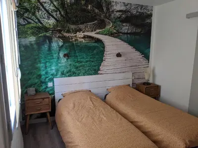 a bed in a bedroom with a painting of a river at LA MAISON MIRAVA in La Caunette