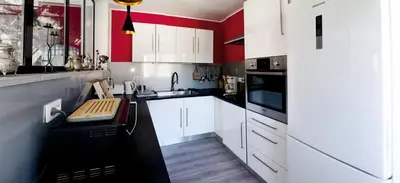 a kitchen with white cabinets and red walls at LA MAISON MIRAVA in La Caunette