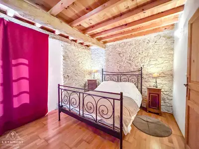 a bedroom with a black bed in a stone wall at Charme rustique avec jardin privé 
