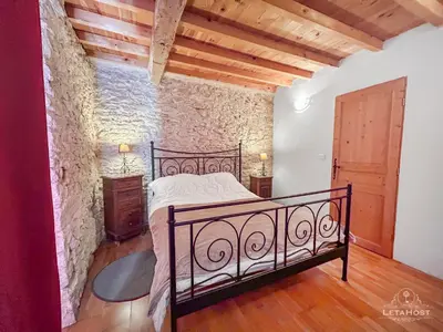 a bedroom with a bed and a stone wall at Charme rustique avec jardin privé 