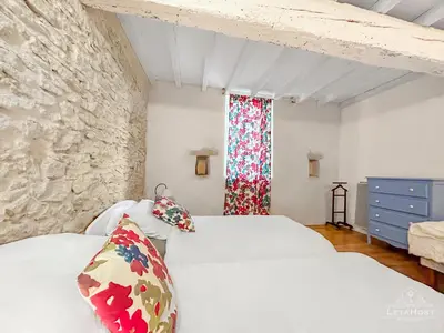 a bedroom with two beds and a window at Charme rustique avec jardin privé 