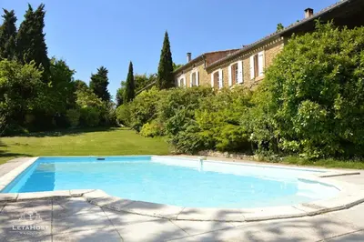 a large blue swimming pool in front of a house at Charme rustique avec jardin privé 