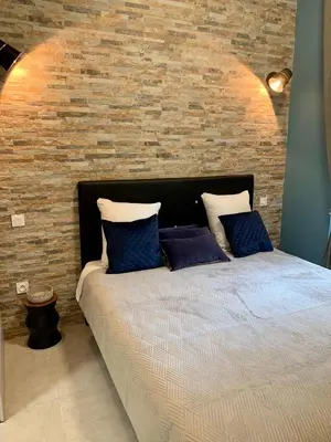 a bed with blue pillows in front of a brick wall at LE 31 in Carcassonne
