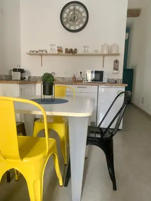a kitchen with yellow chairs and a table and a clock at LE 31 in Carcassonne