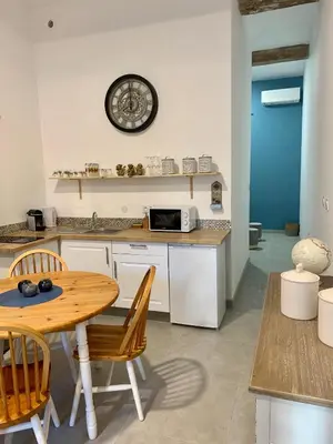 a kitchen with a table and a clock on the wall at LE 31 in Carcassonne