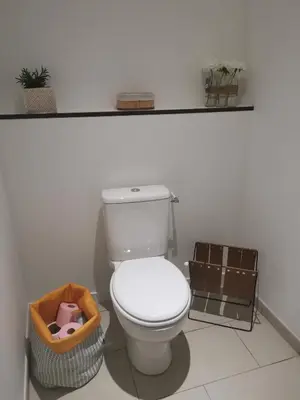a white bathroom with a toilet and a basket at La Maison Cachée in Carcassonne