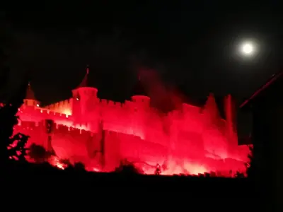 a castle lit up with red lights at night at La Maison Cachée in Carcassonne