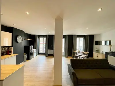 a living room and kitchen with a couch and a table at Spacieux Appartement Lumineux Cœur De Ville in Pamiers