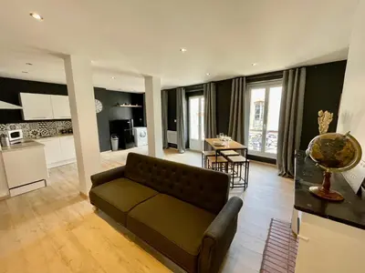 a living room with a couch and a kitchen at Spacieux Appartement Lumineux Cœur De Ville in Pamiers