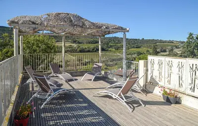 a group of chairs on a deck with an umbrella at Chambre La Caunette in La Caunette