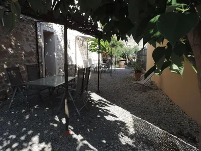 a table and chairs in the shade of a building at Gîtes Le 
