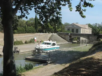 a boat is docked in a river near a bridge at Gîtes Le 