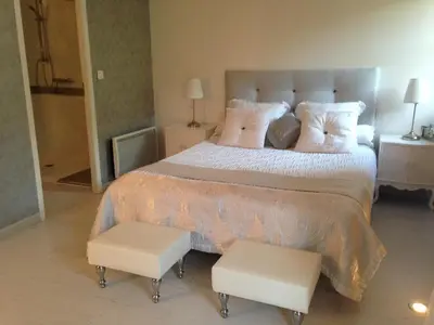a bedroom with a large bed with two white chairs at Au Paradis Cathare in Fraissé-des-Corbières