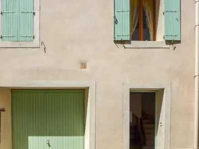 two green doors and windows on a building at Holiday Home La Maison de l'Etang by Interhome in Gruissan