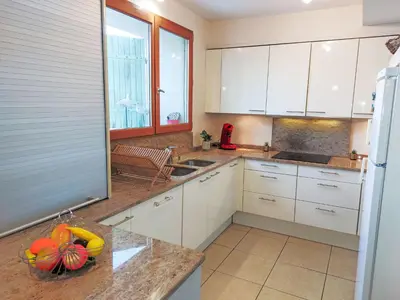 a kitchen with white cabinets and a bowl of fruit on a counter at Holiday Home La Maison de l'Etang by Interhome in Gruissan