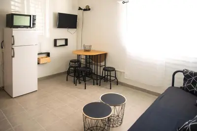 a living room with a table and chairs and a refrigerator at le studio du Grazel in Gruissan