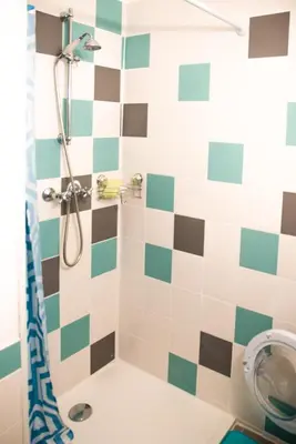 a bathroom with a shower with green and white tiles at le studio du Grazel in Gruissan