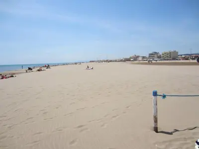 a beach with people sitting on the sand at Ferienhaus Le Château in Armissan