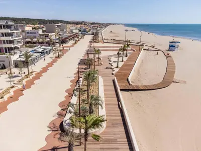 a sandy beach with palm trees and a boardwalk at Designer Haus in Armissan