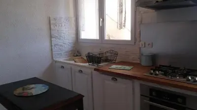 a kitchen with white cabinets and a sink and a window at GITE PAPY ALBERT in Gruissan