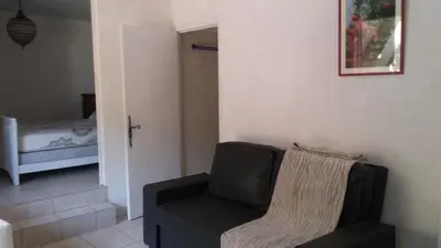 a living room with a chair and a bed at GITE PAPY ALBERT in Gruissan