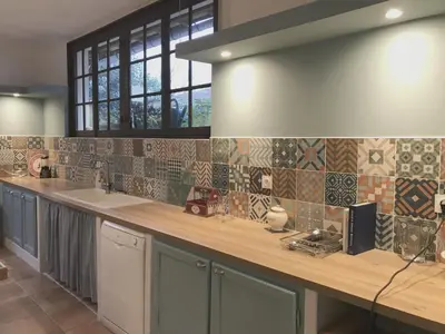 a kitchen with a counter with tiles on the wall at Hibiscus House in Carcassonne