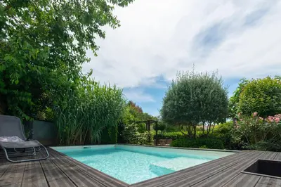 a swimming pool with a deck and a chair next to it at Hibiscus House in Carcassonne
