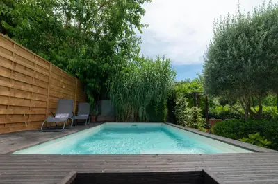 a swimming pool in a backyard with a wooden deck at Hibiscus House in Carcassonne