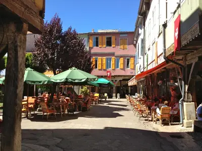 an empty street with tables and chairs and umbrellas at Stay, Saint-André-de-Roquelongue in Saint-André-de-Roquelongue