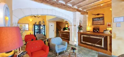 a living room with two chairs and a fireplace at Hotel du Mas in Vinassan